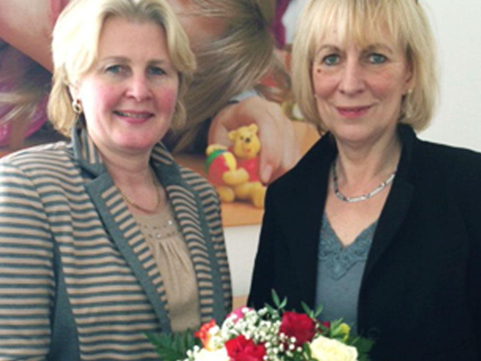 Zwei Frauen stehen zusammen und halten bunte Blumen.