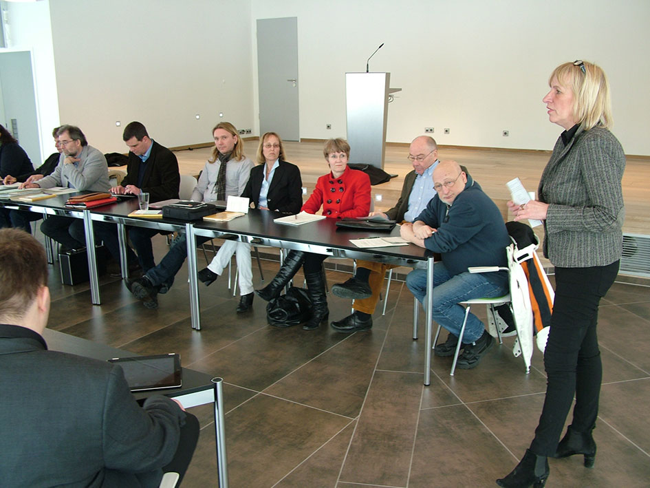 Eine Frau steht vor einer Gruppe und gibt eine Präsentation.