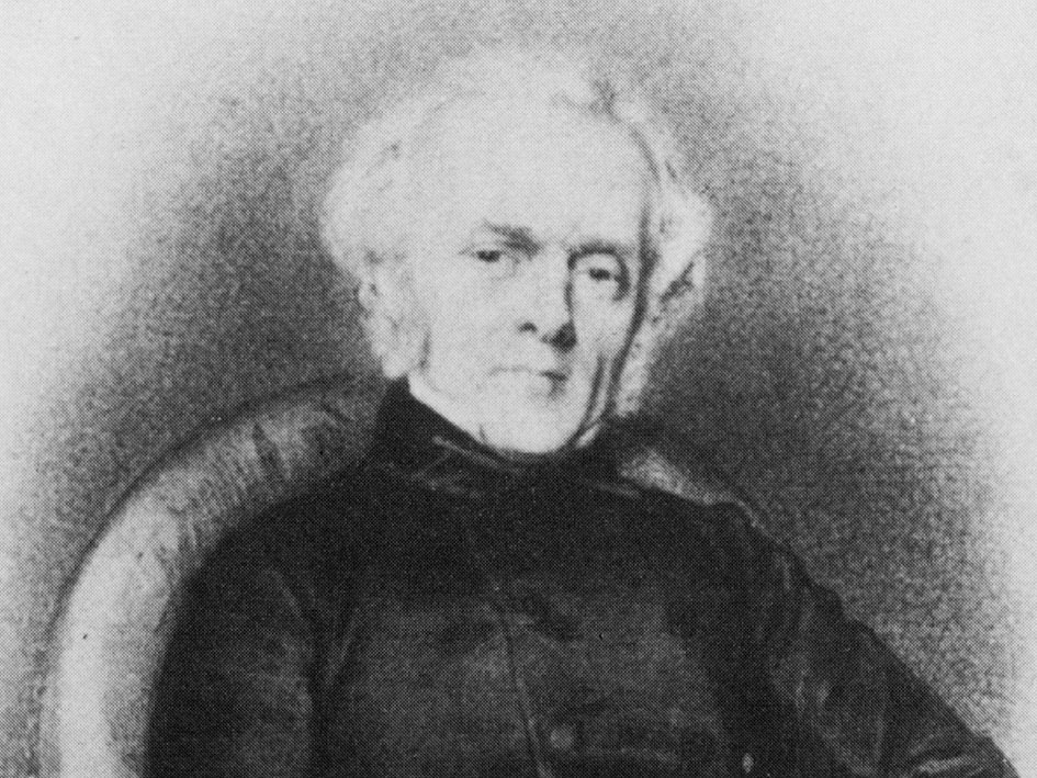 Schwarz-Weiß-Foto eines Mannes in einem eleganten schwarzen Mantel aus der Vergangenheit.