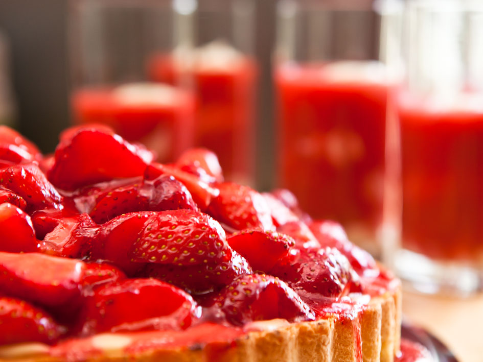 Erdbeerkuchen mit frischen Erdbeeren obendrauf, auf einem weißen Teller serviert.