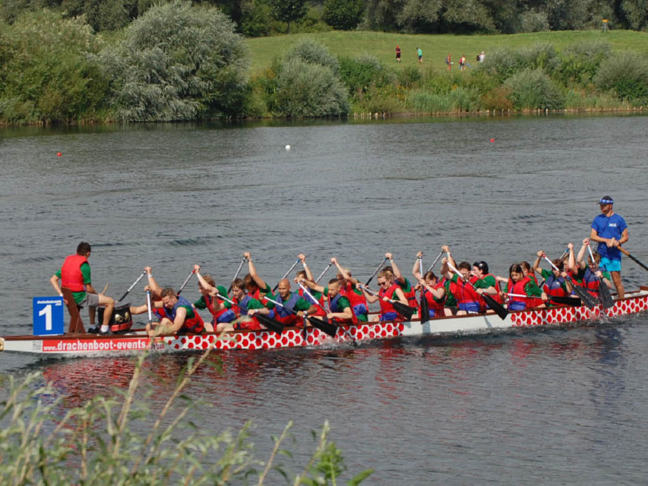 Eine Gruppe von Menschen auf einem Boot hebt die Hände in die Luft und feiert den Moment.