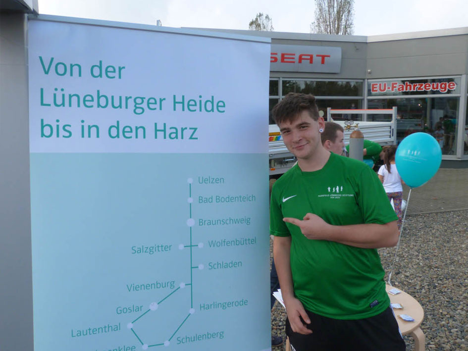 Ein Mann steht neben einem Schild, das Informationen oder Richtungen anzeigt.