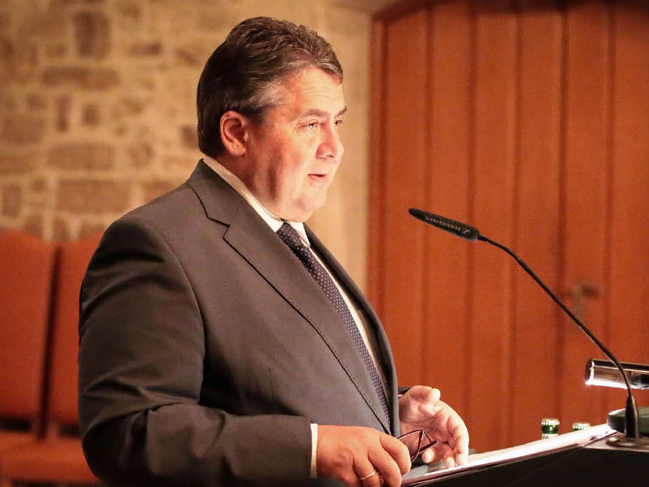 Ein Mann in einem Anzug und einer Krawatte präsentiert vor einem Publikum.