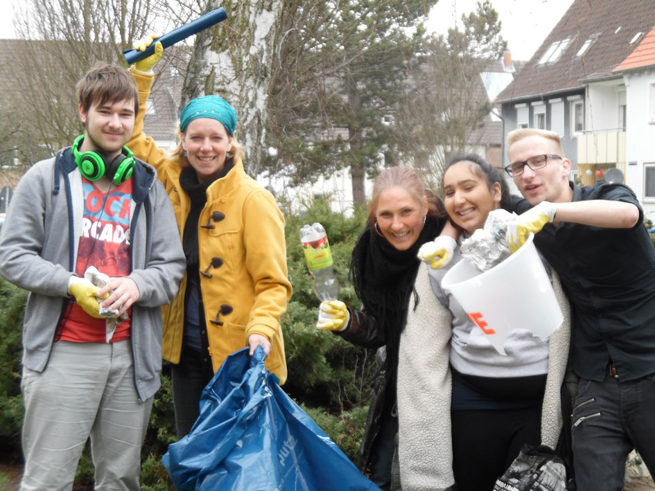 Eine Gruppe von Menschen hält Müllsäcke und beteiligt sich an einer Aufräumaktion im Freien.
