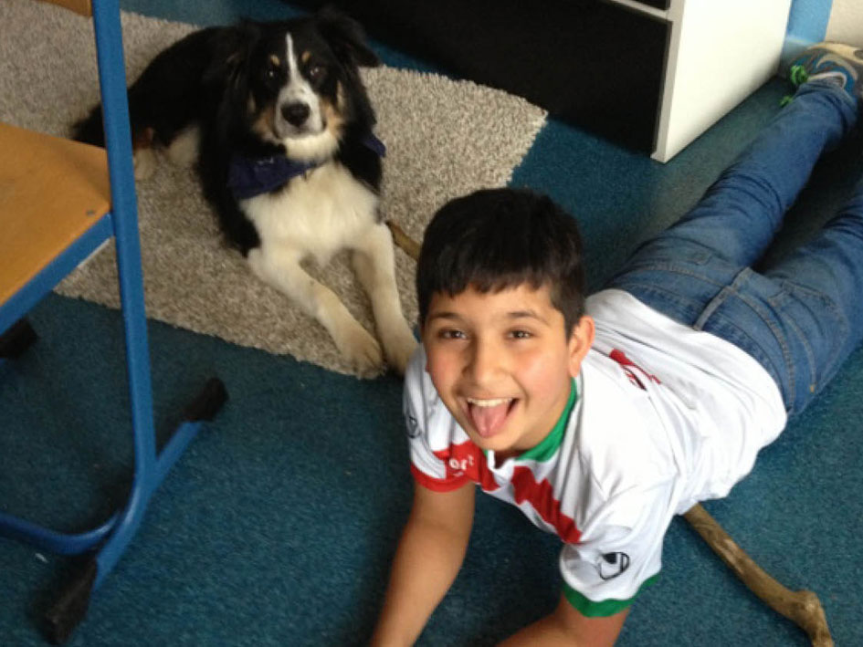 Ein Junge liegt auf dem Boden neben einem Hund und spielt entspannt mit ihm.