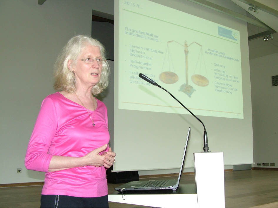 Eine Frau steht vor einem Laptop und lächelt, während sie den Bildschirm betrachtet.