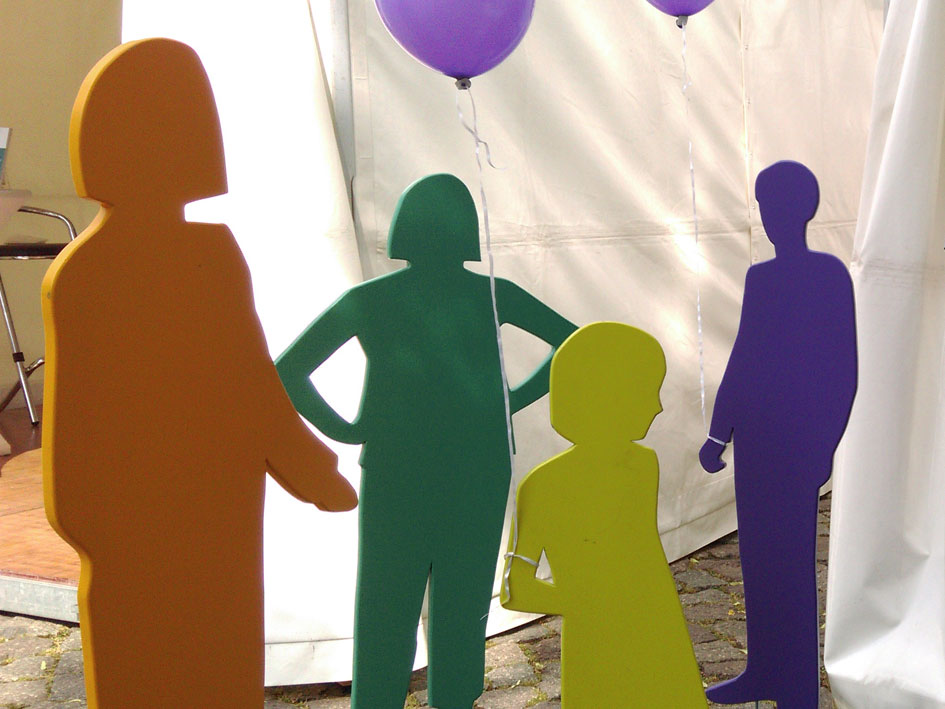 Eine Gruppe von Menschen steht vor einem Zelt und unterhält sich.