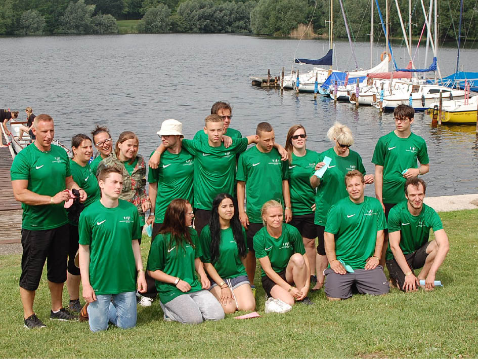 Mehrere Personen in grünen Shirts versammeln sich lächelnd in einer entspannten Umgebung.