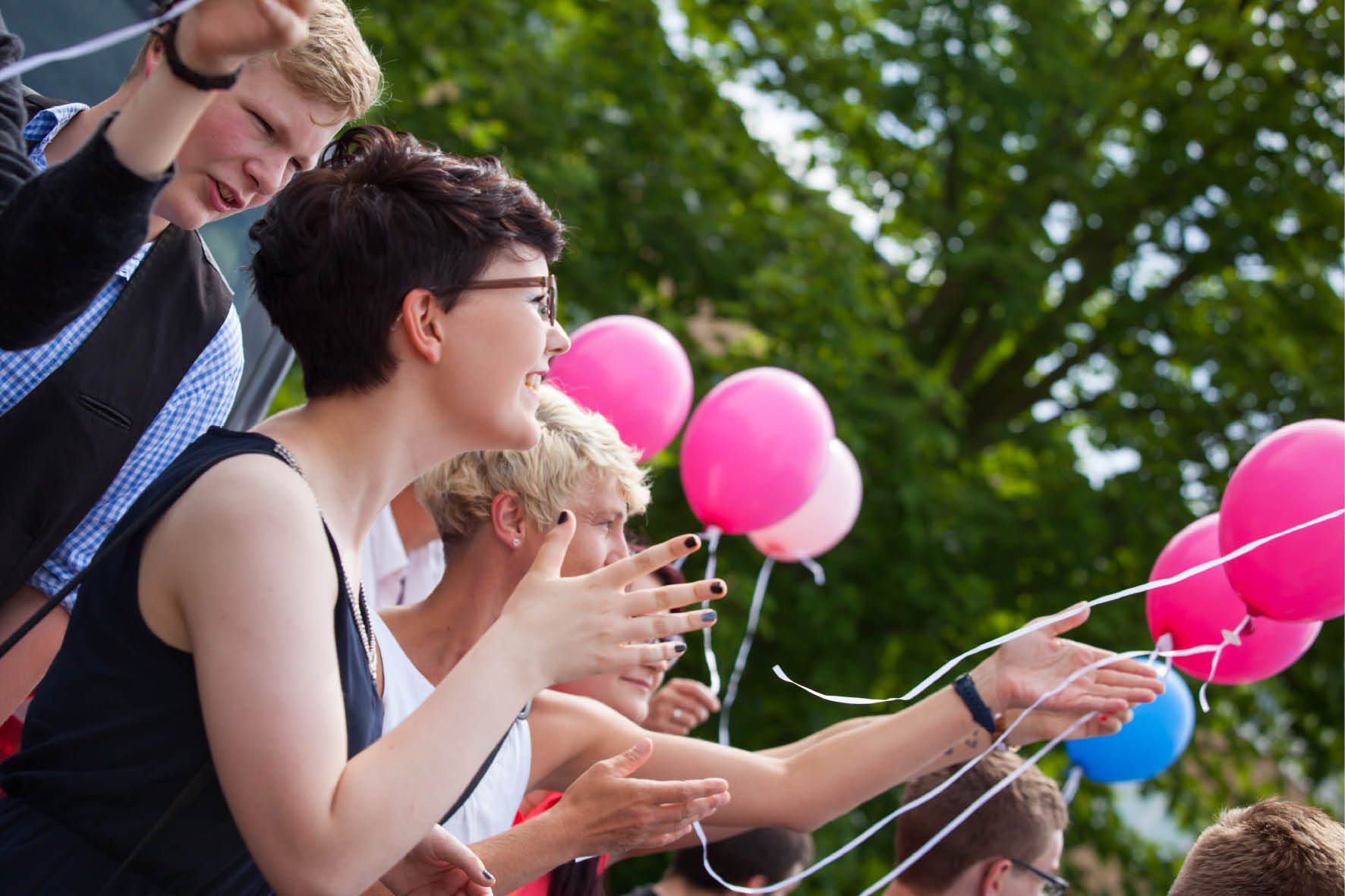 Eine fröhliche Versammlung von Personen, die bunte Ballons in den Händen halten.