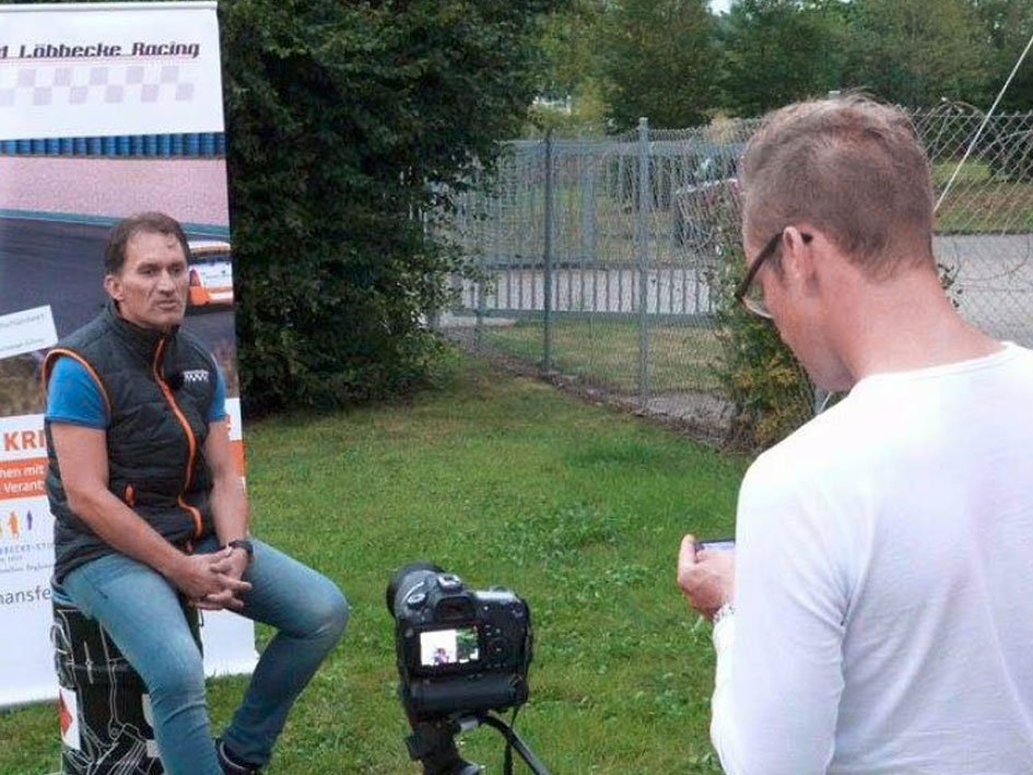 Ein Mann sitzt auf einem Stuhl und spricht in die Kamera.