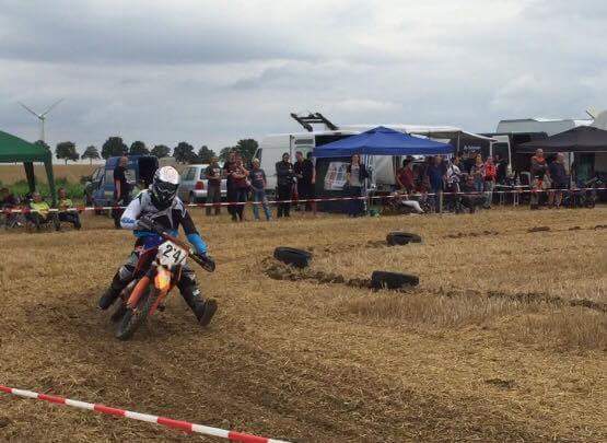 Ein Dirtbike-Fahrer fährt über ein Feld in der Natur.