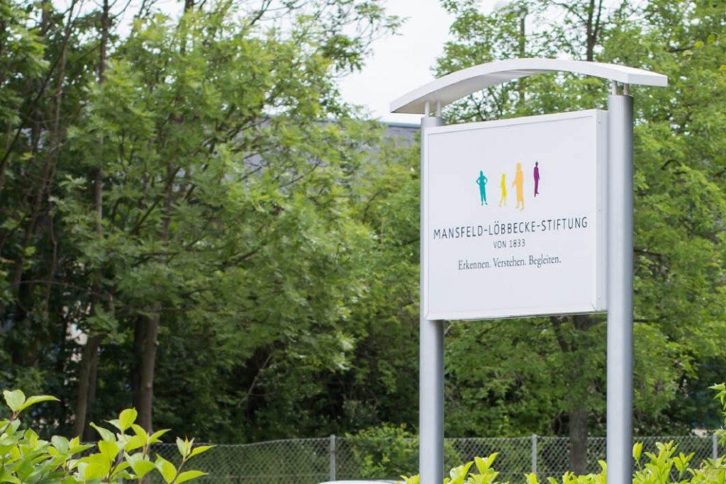 Schild des Kinderzentrums, umgeben von Bäumen, das den Standort für Familien und Kinder anzeigt.