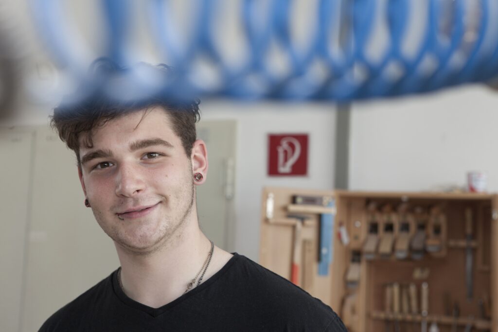 Lächelnder junger Mann vor einem Hintergrund aus blauem Draht.