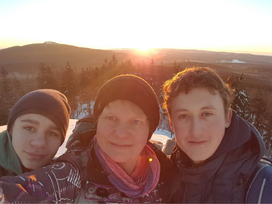 Drei Freunde posieren für ein Selfie im Schnee, lächelnd und fröhlich.