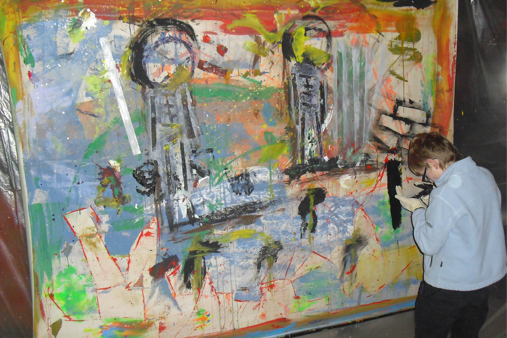 Eine Frau malt ein großes Bild auf einer Leinwand.