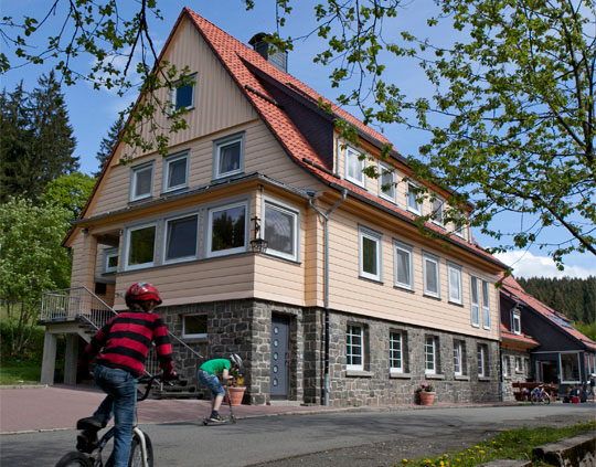 Ferienhaus im Harz mit Kindern auf Fahrrädern und Rollern vor dem Haus. Urlaub in Deutschland, Familienurlaub.