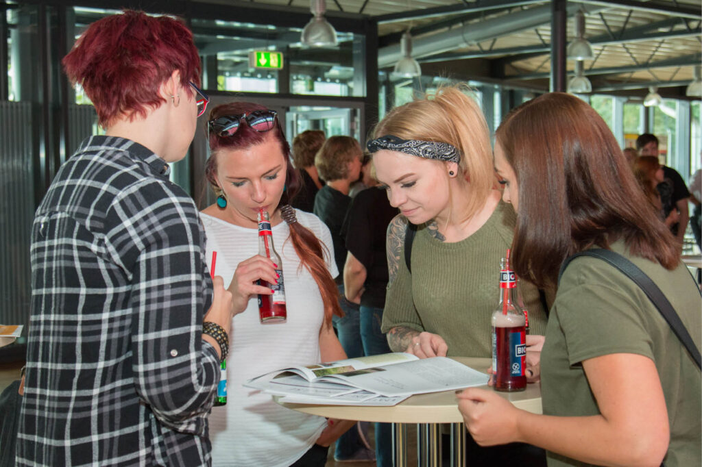 Junge Frauen lesen gemeinsam Zeitschrift und trinken Saft. Studentenpause, Studentenleben, Freizeitaktivitäten.