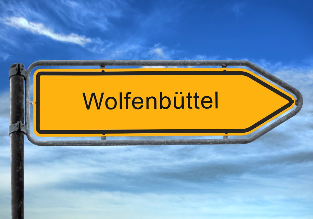 Gelbes Ortsschild Wolfenbüttel vor blauem Himmel. Reiseziel Wolfenbüttel in Niedersachsen, Deutschland. Ausflugsziel.