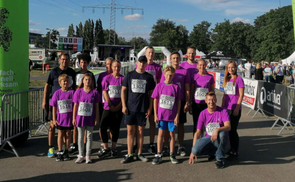 Laufteam beim Firmenlauf: Gruppe von Läufern in lila T-Shirts vor dem Start. Sportveranstaltung, Marathon, Jogging, Teamgeist.