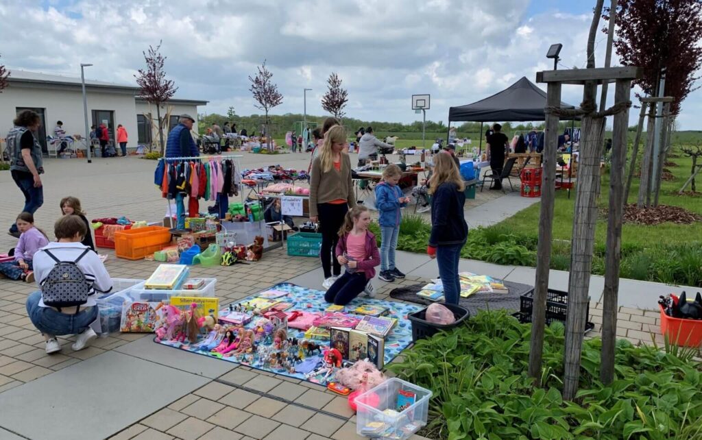 Flohmarkt im Freien: Kinder verkaufen Spielzeug, Bücher und Kleidung. Schnäppchenjagd auf dem Trödelmarkt. Gebrauchte Waren für Kinder.