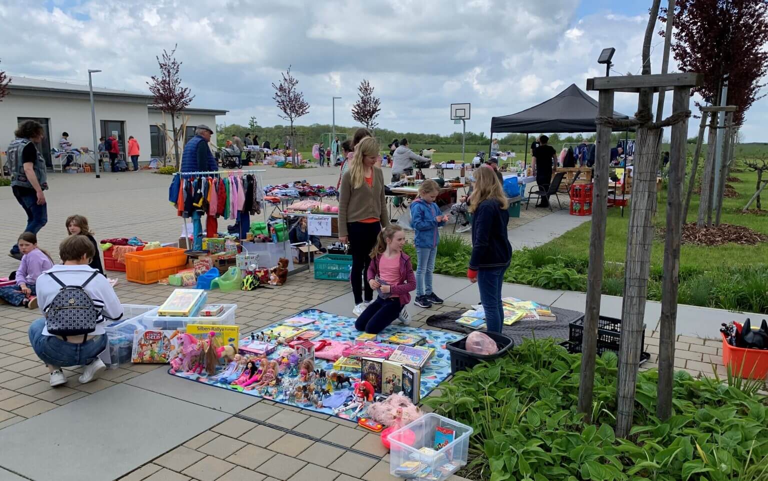 Flohmarkt im Freien: Kinder verkaufen Spielzeug, Bücher und Kleidung. Schnäppchenjagd auf dem Trödelmarkt. Gebrauchte Waren für Kinder.