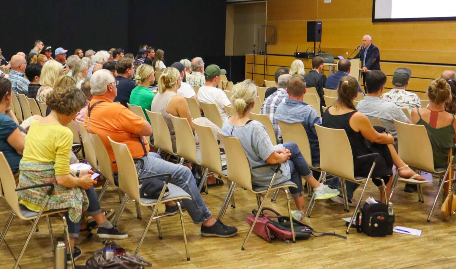 Publikum hört Vortrag von Redner auf Bühne zu. Konferenz, Seminar oder Schulung mit vielen Zuhörern in Halle.