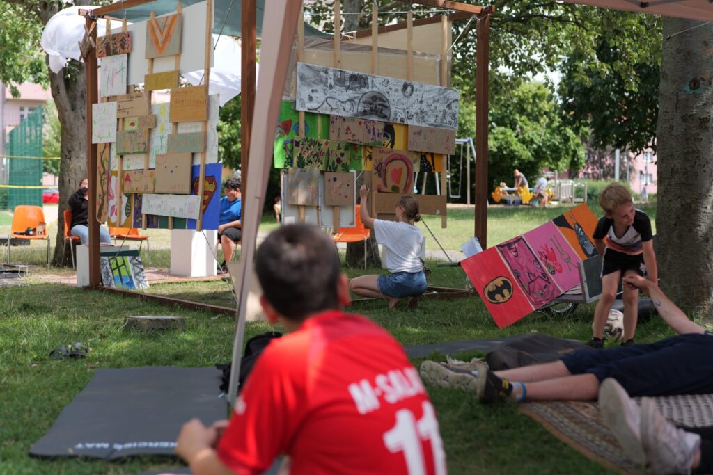 Kunstaktion im Park: Kinder gestalten Bilderrahmen, kreative Kunstprojekte im Freien, Sommeraktivitäten für Familien.