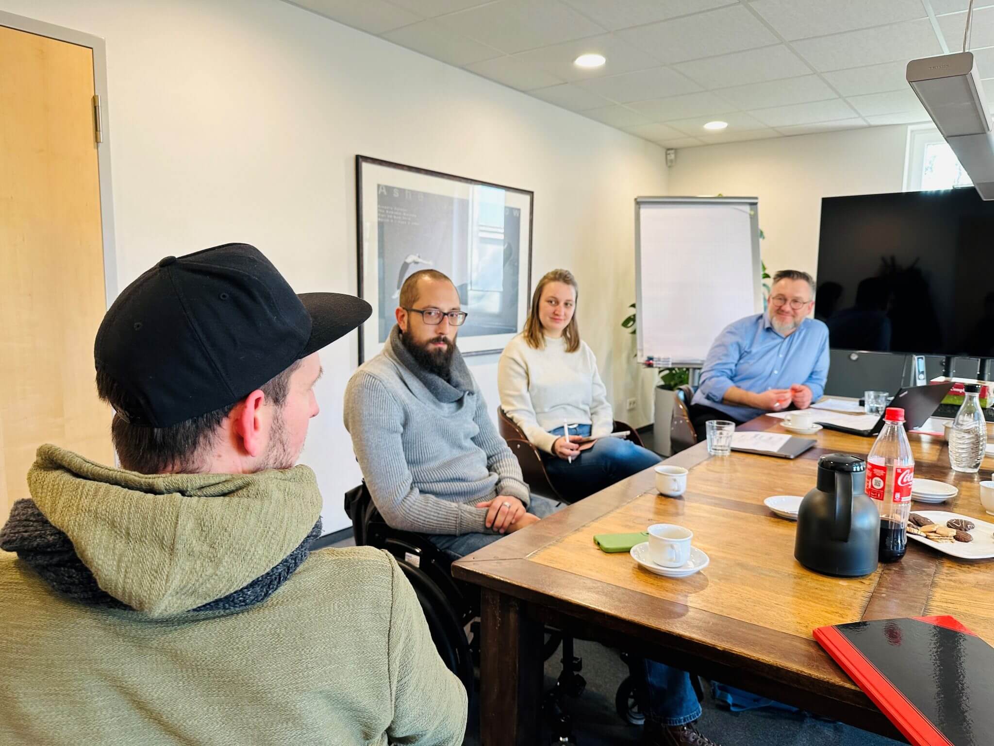 Eine Gruppe von Menschen sitzt an einem Tisch in einem Büro und diskutiert.