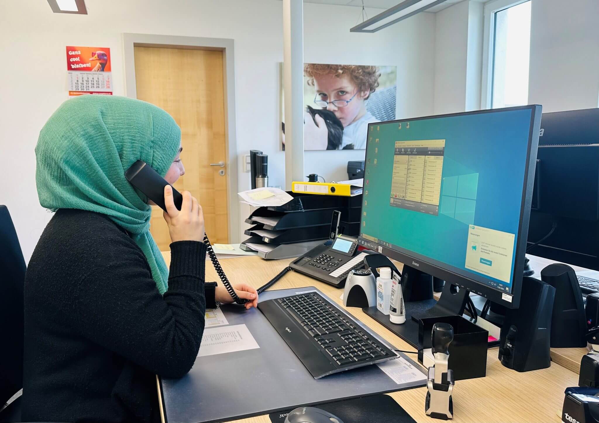 Eine Frau im Hijab arbeitet an einem Computer an ihrem Schreibtisch.