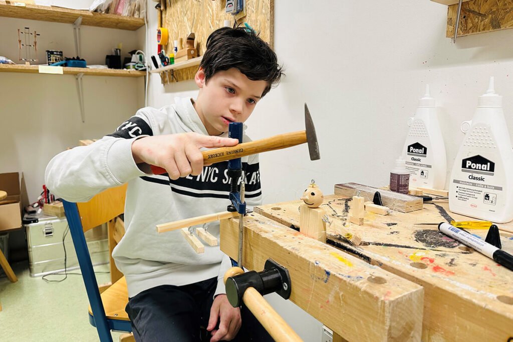 Ein junger Mann arbeitet konzentriert an einer Holzwerkbank.
