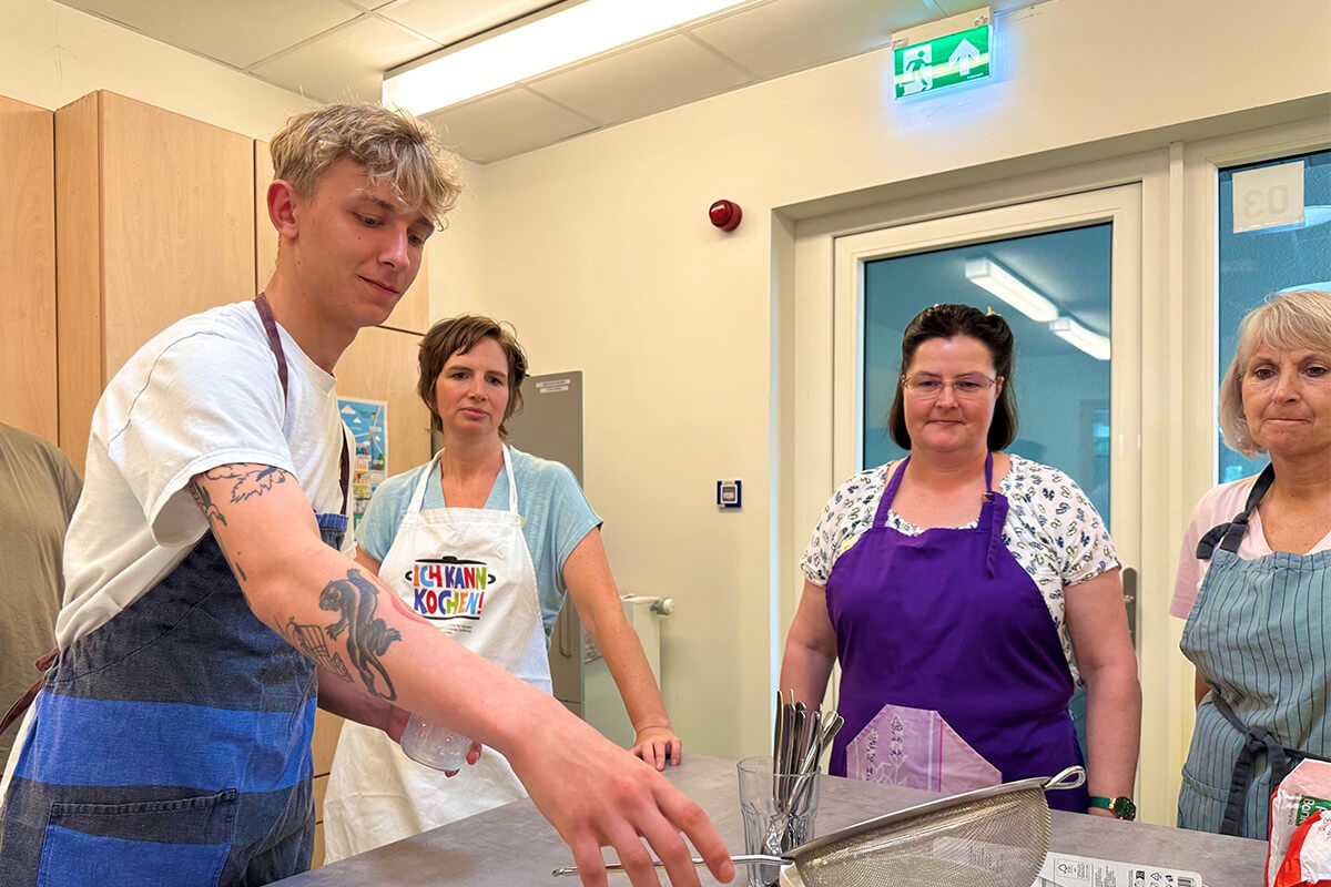 Menschen stehen um einen Tisch, auf dem ein Messer platziert ist.