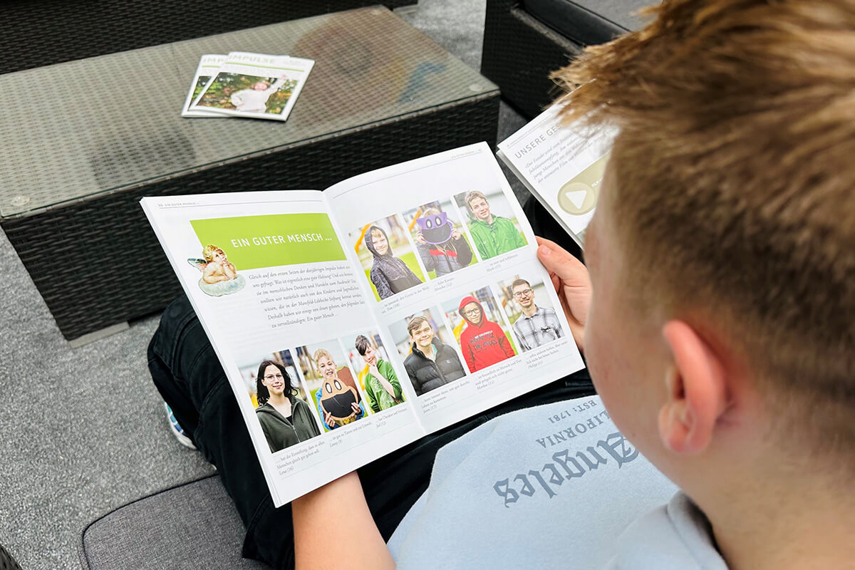 Ein junger Junge liest eine Zeitschrift auf einer Terrasse.