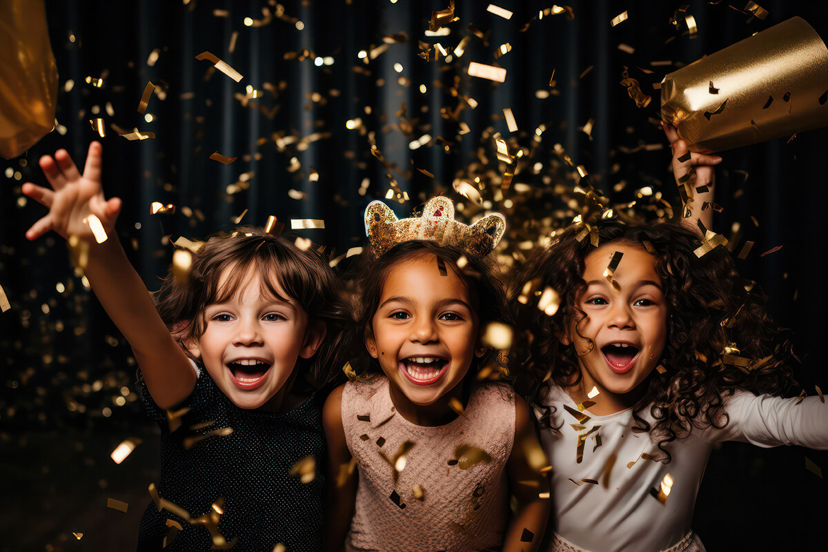 Drei Kinder feiern auf einer Party, umgeben von Konfetti, mit fröhlichen Gesichtern und bunten Luftballons.
