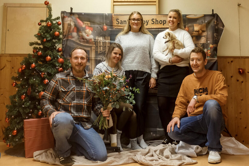Eine Gruppe von Menschen posiert vor einem Weihnachtsbaum für ein Foto.