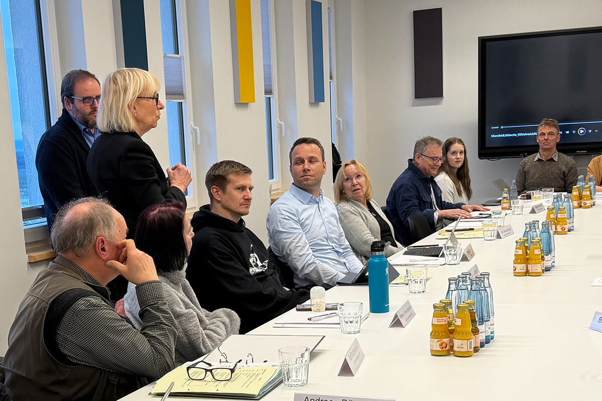 Besprechung in Konferenzraum: Gruppe von Personen sitzt am Tisch, Diskussion, Business Meeting, Konferenz, Teamarbeit, Getränke.