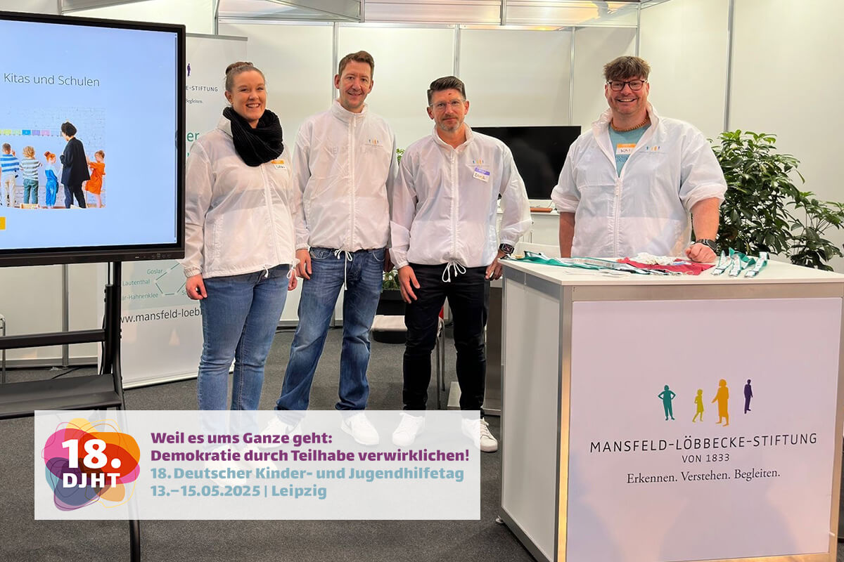 Drei Personen stehen vor einem weißen Tisch.