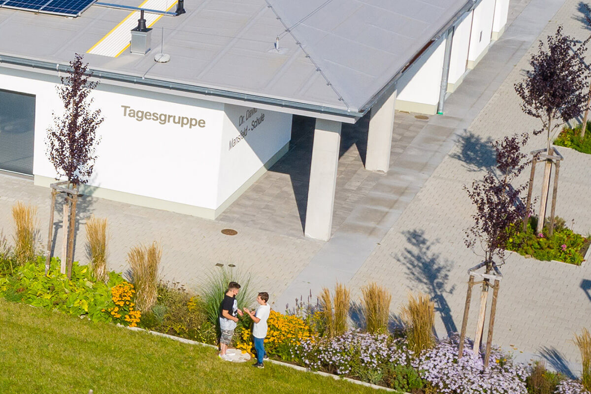 Zwei Personen stehen vor einem Gebäude und unterhalten sich.