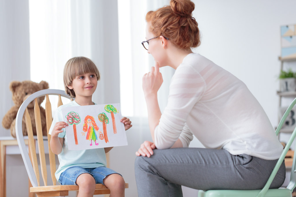 Eine Frau sitzt auf einem Stuhl, während ein Kind ein Blatt Papier in der Hand hält.