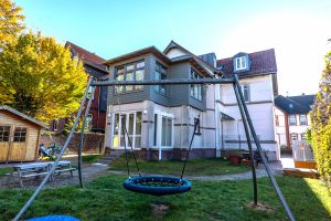 Schaukelset im Garten eines Wohnhauses, ideal für Kinder zum Spielen.