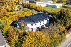 Eine bunte Schaukel steht im Garten eines Hauses, bereit für Kinder.