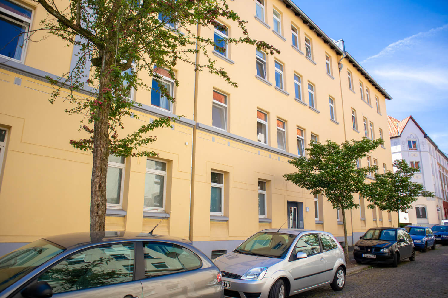 Gelbes Gebäude mit parkenden Autos davor.