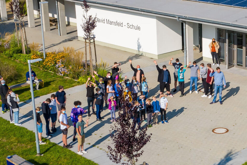 Mehrere Personen posieren vor einem großen Gebäude, alle blicken freundlich.