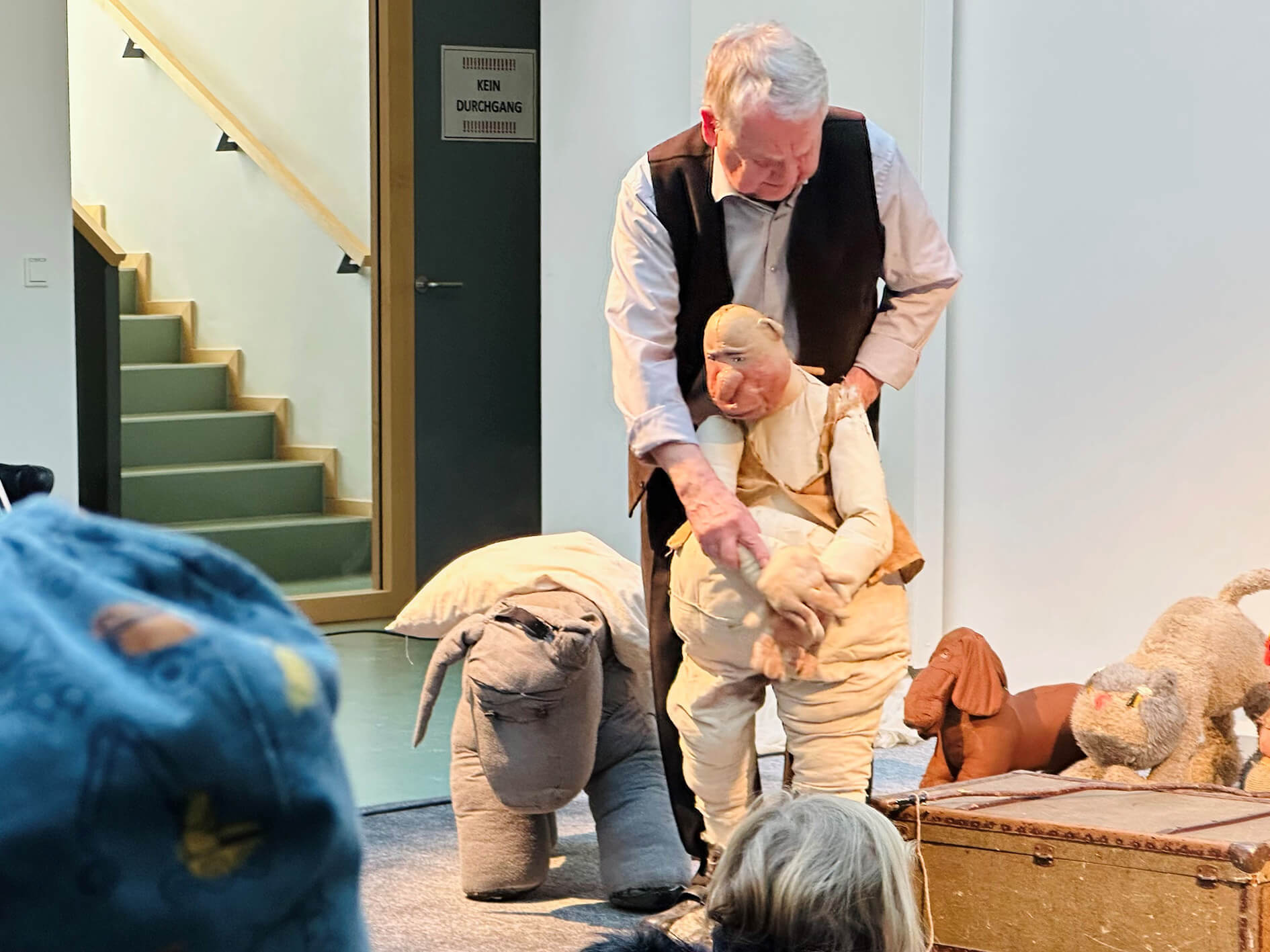 Ein Mann hilft einem Stofftier, aufzustehen.