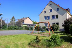 Ein Haus mit einer Schaukel im Garten.