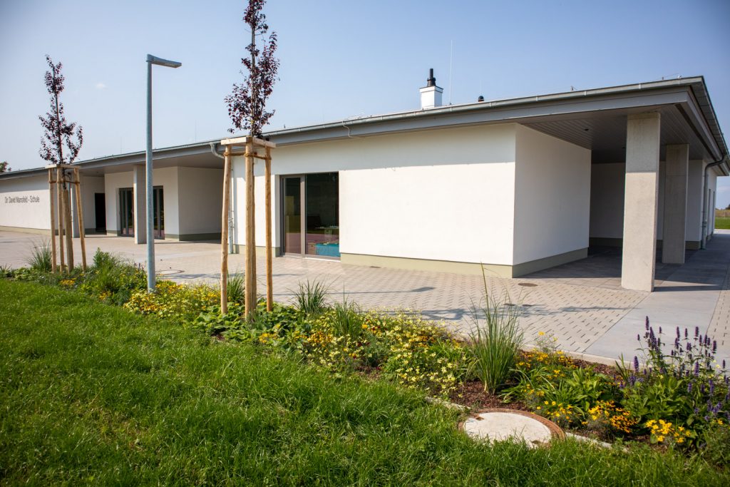 Ein Gebäude mit einer grünen Fläche und einem Baum davor.