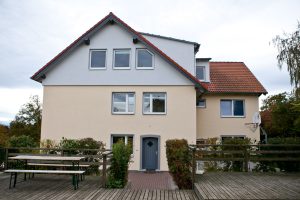 Ein Haus mit einem Picknicktisch davor, umgeben von Rasen und Bäumen.