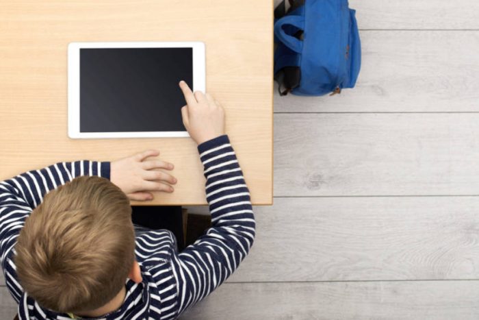 Ein Junge sitzt an einem Tisch und nutzt ein Tablet-Computer.