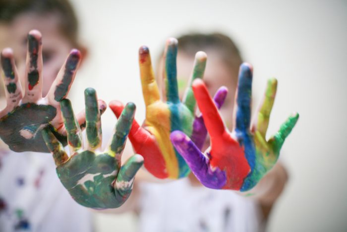 Bunte Kinderhände, die mit verschiedenen Farben bemalt sind, zeigen Kreativität und Freude.